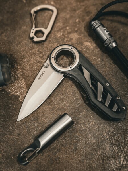 Gerber folding knife with a thumb hole in the blade placed among EDC gear.
