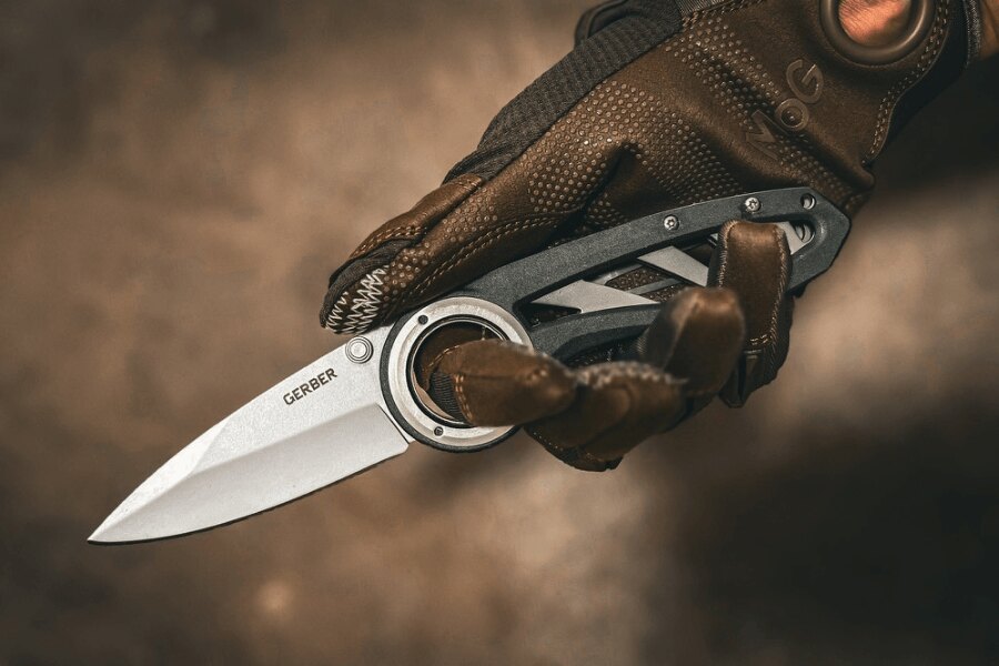 Open Gerber folding knife held by a person wearing a tactical glove.