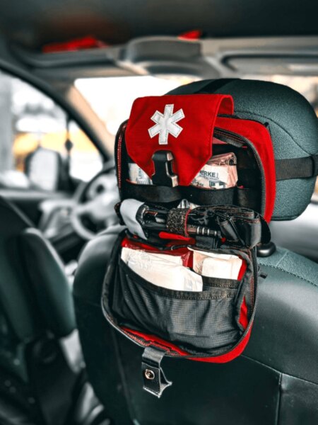 Open first aid kit attached to the headrest of a front vehicle seat.