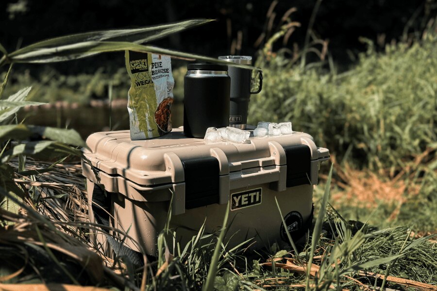 A YETI LoadOut GoBox with packaged food and insulated drinkware outdoors.