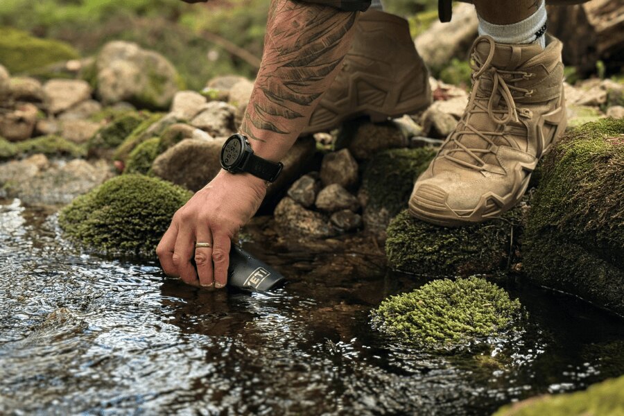 Collecting water from a forest stream in a YETI bottle.