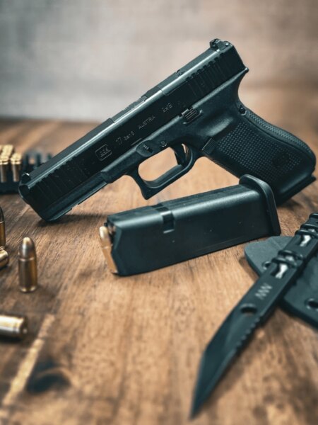 Glock 17 Gen5 pistol with iron sights placed on a table with a magazine, ammunition and a knife.