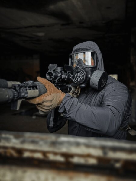 Shooter wearing an AVEC full-face protective mask with a filter while aiming a rifle.