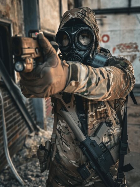 Shooter wearing a full-face protective mask with a filter while aiming a pistol.