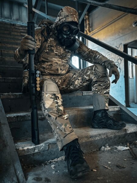 User wearing a full-face protective mask with a filter and tactical gear on a staircase.