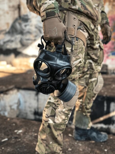 Close-up of a full-face protective mask with a filter being held in one hand.