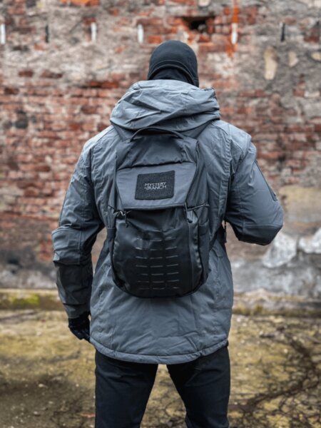 Grey Mystery Ranch Rip Ruck 20 backpack worn by a user in front of a brick wall.