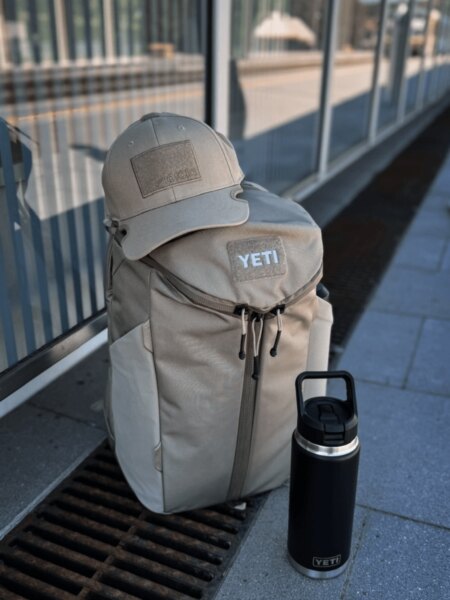 Green YETI Crossroads 27L backpack with a cap, sunglasses, and a black YETI Rambler.