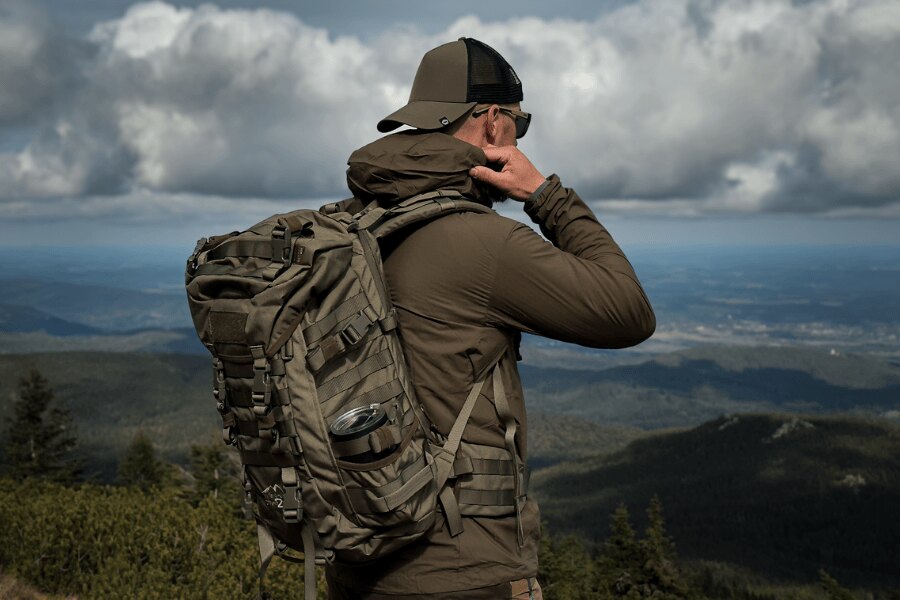 Man wearing a Wisport SilverFox 2 backpack on a mountain ridge beneath storm clouds.