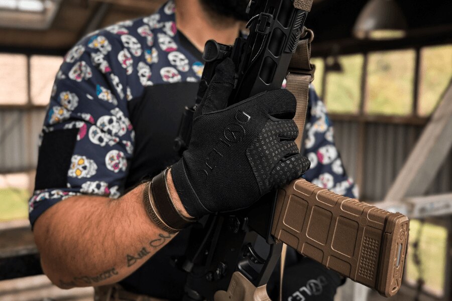 Close-up of black Dýlejc Bivoj shooting gloves while holding a rifle with a magazine inserted.