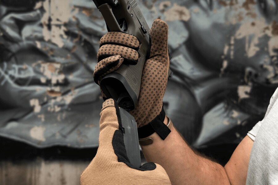 Close-up of Dýlejc Bivoj glove palms with rubberized grip dots while handling a pistol.