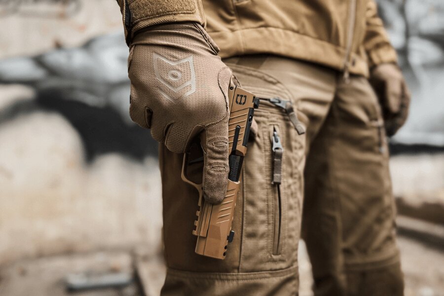 Shooter wearing a tan glove holds a tan SIG Sauer pistol alongside the thigh.