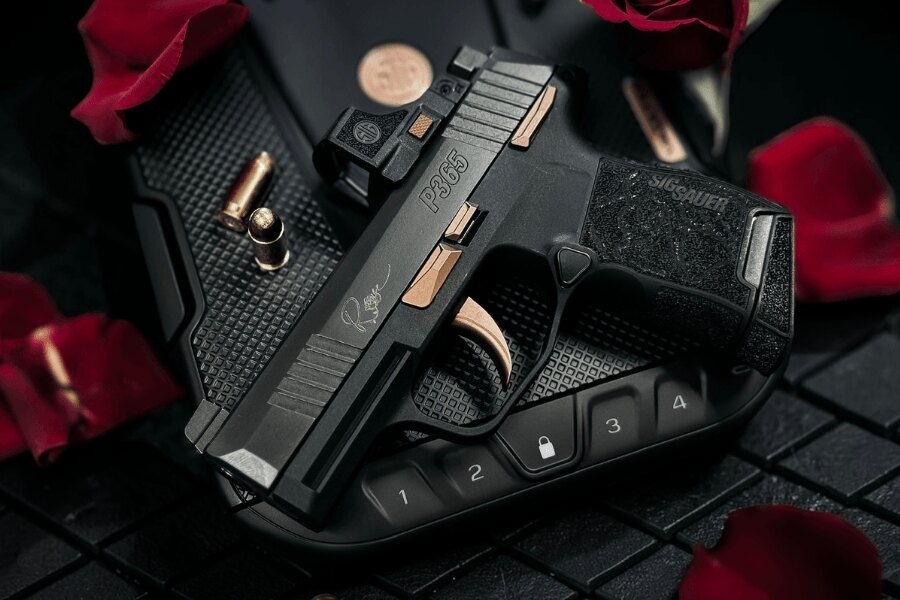 SIG Sauer P365 ROSE pistol with a red dot sight and rose-gold accents, displayed on a lockable case among rose petals.