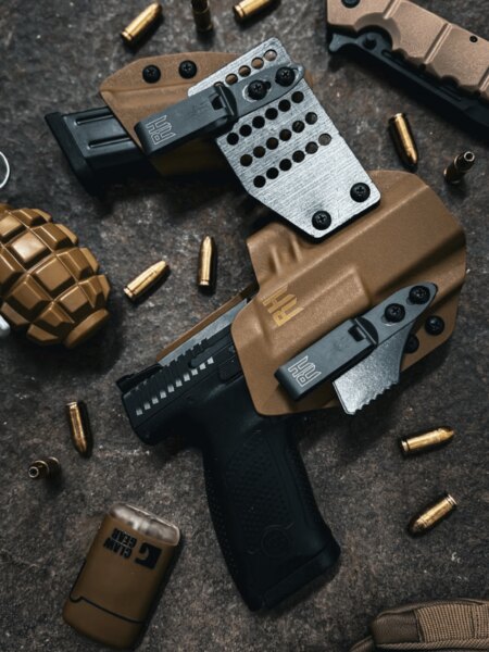 A brown Kydex holster system for a handgun and spare magazine, joined by metal hardware and fitted with two attachment clips.